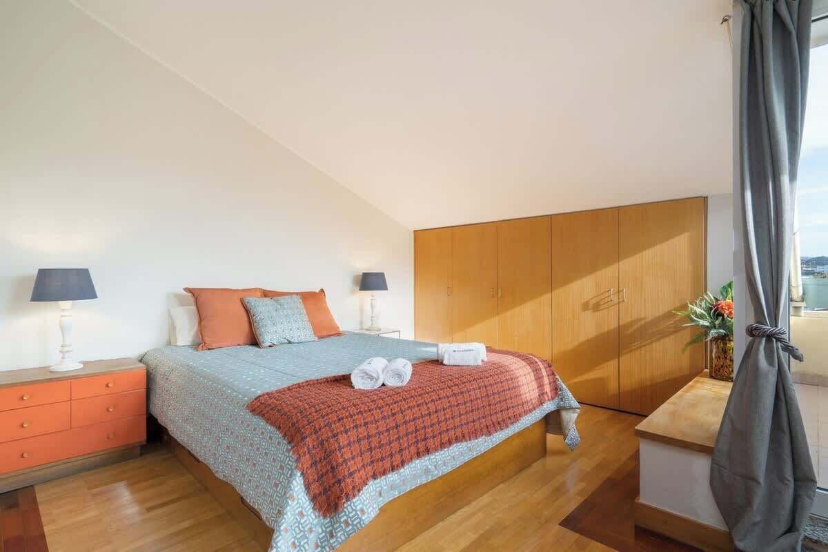 A bedroom with a bed, nightstands, a wooden wardrobe, and a window with curtains.