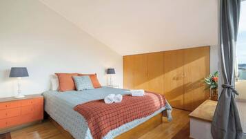 A bedroom with a bed, nightstands, a wooden wardrobe, and a window with curtains.