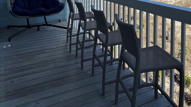 Una terrazza in legno con un'amaca e sedie in vimini che si affaccia su una spiaggia.