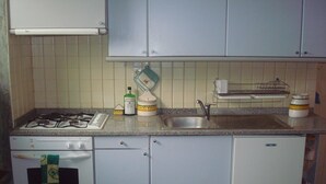 Una cocina compacta con estufa a gas, lavaplatos y fregadero.