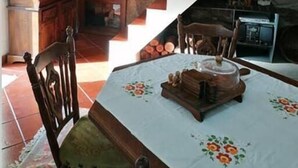 Un comedor con una mesa preparada para dos personas, una silla de madera y una escalera que sube a un nivel superior.
