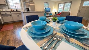 Comedor con una mesa redonda dispuesta para cuatro personas, con vajilla y cubiertos azules.