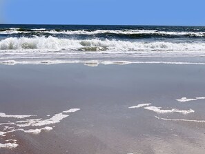 Ein Strand mit brechenden Wellen und einem klaren Himmel.