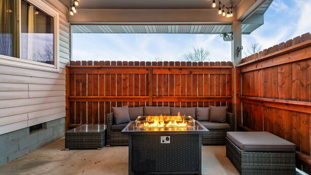 An outdoor patio with a glass-top fire feature, wicker furniture, and a wooden fence. - Dog Friendly Home, Arcade Game, Near Pigeon Forge (Pigeon Forge)