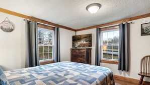 A bedroom with a large bed, wooden floor, and a window with curtains. - Dog Friendly Home, Arcade Game, Near Pigeon Forge (Pigeon Forge)