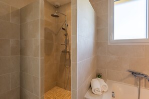 Een bad/douchecombinatie, handdoeken, toiletpapier