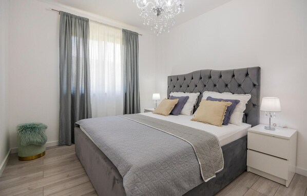 A modern bedroom with a tufted headboard, a grey quilted bedspread, and a green furry stool. - Lovely home in Donji Prolozac (Donji Prolozac)