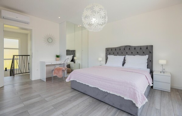 A modern bedroom with a large bed, a desk, and a chair.