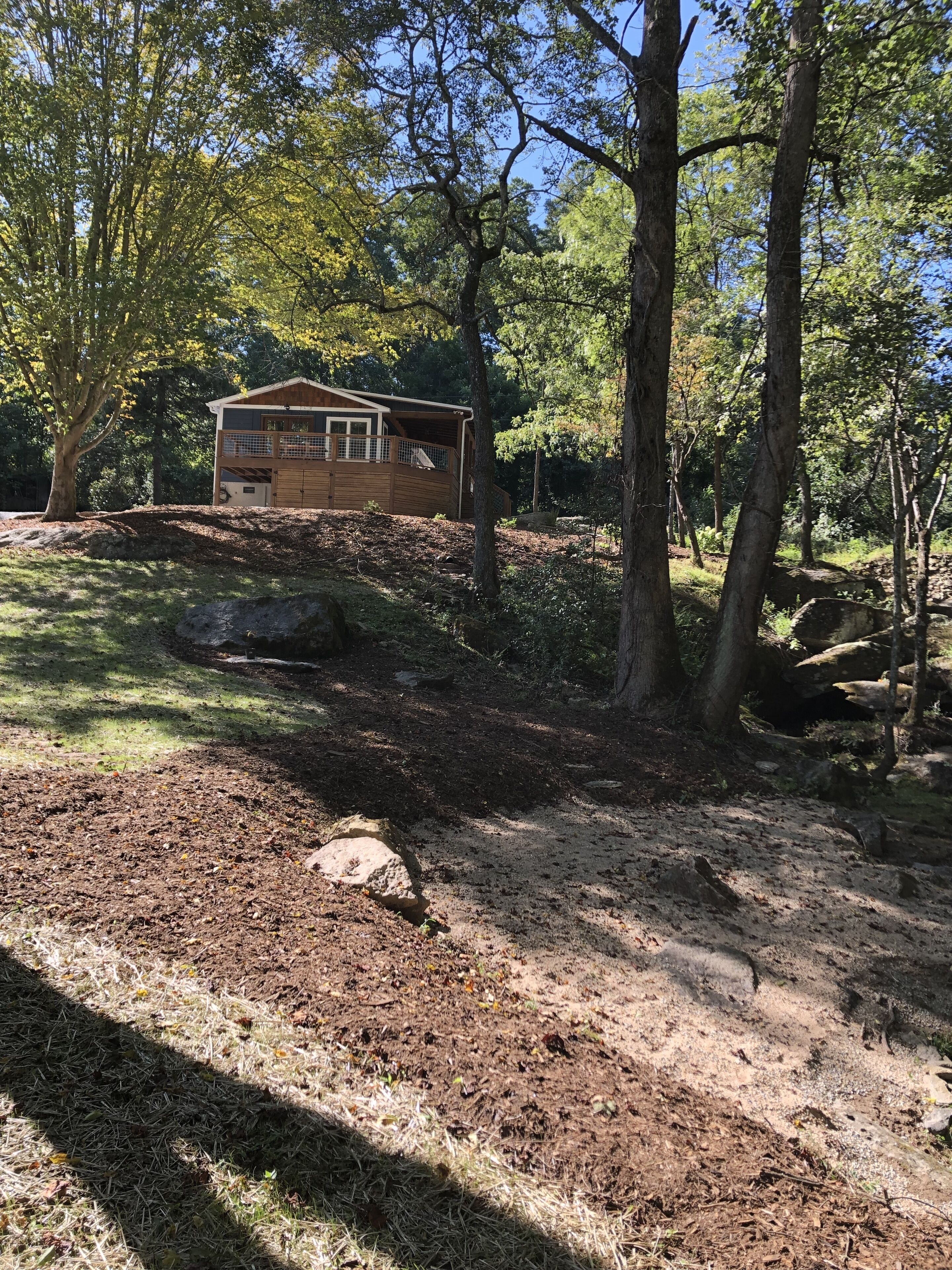 Una cabaña en un área boscosa con un sendero de tierra que lleva a ella.