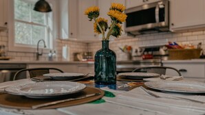 Una cocina con armarios blancos, un microondas y un florero con flores amarillas en la encimera.
