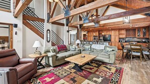 A spacious living area with a high ceiling, exposed wooden beams, a fireplace, and a cozy seating arrangement.