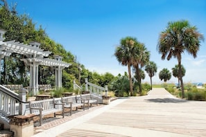 A wooden boardwalk with benches and a pergola structure.