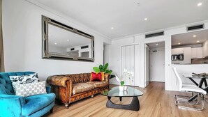 Un salon moderne avec un fauteuil bleu, un canapé en cuir marron et une table basse en verre.