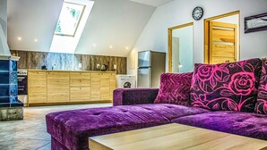 A modern kitchen with a built-in oven and a refrigerator, a purple sofa with floral cushions, and a wooden dining table. - Awesome apartment in Gdansk with WiFi (Gdansk)