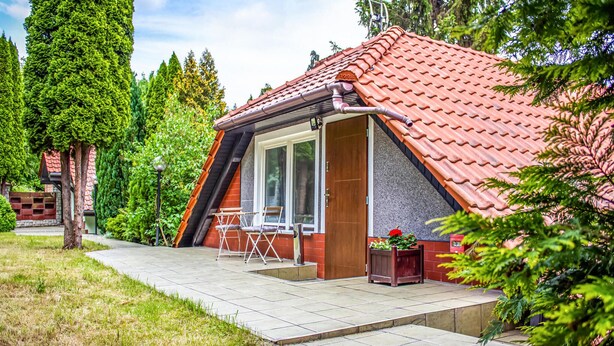 A small, single-story house with a red-tiled roof, a glass door, and a patio with a table and chairs. - Awesome apartment in Gdansk with WiFi (Gdansk)