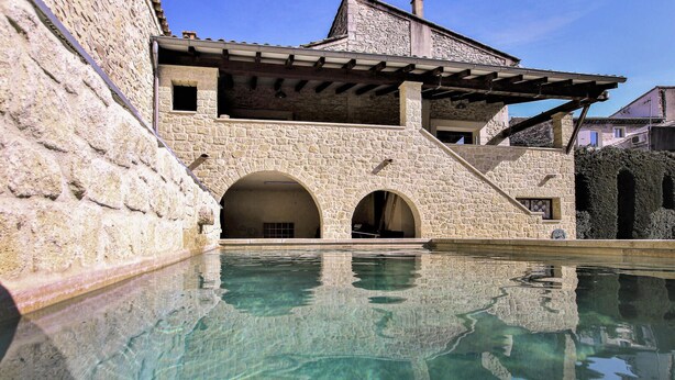 Un edificio de piedra con una piscina delantera.