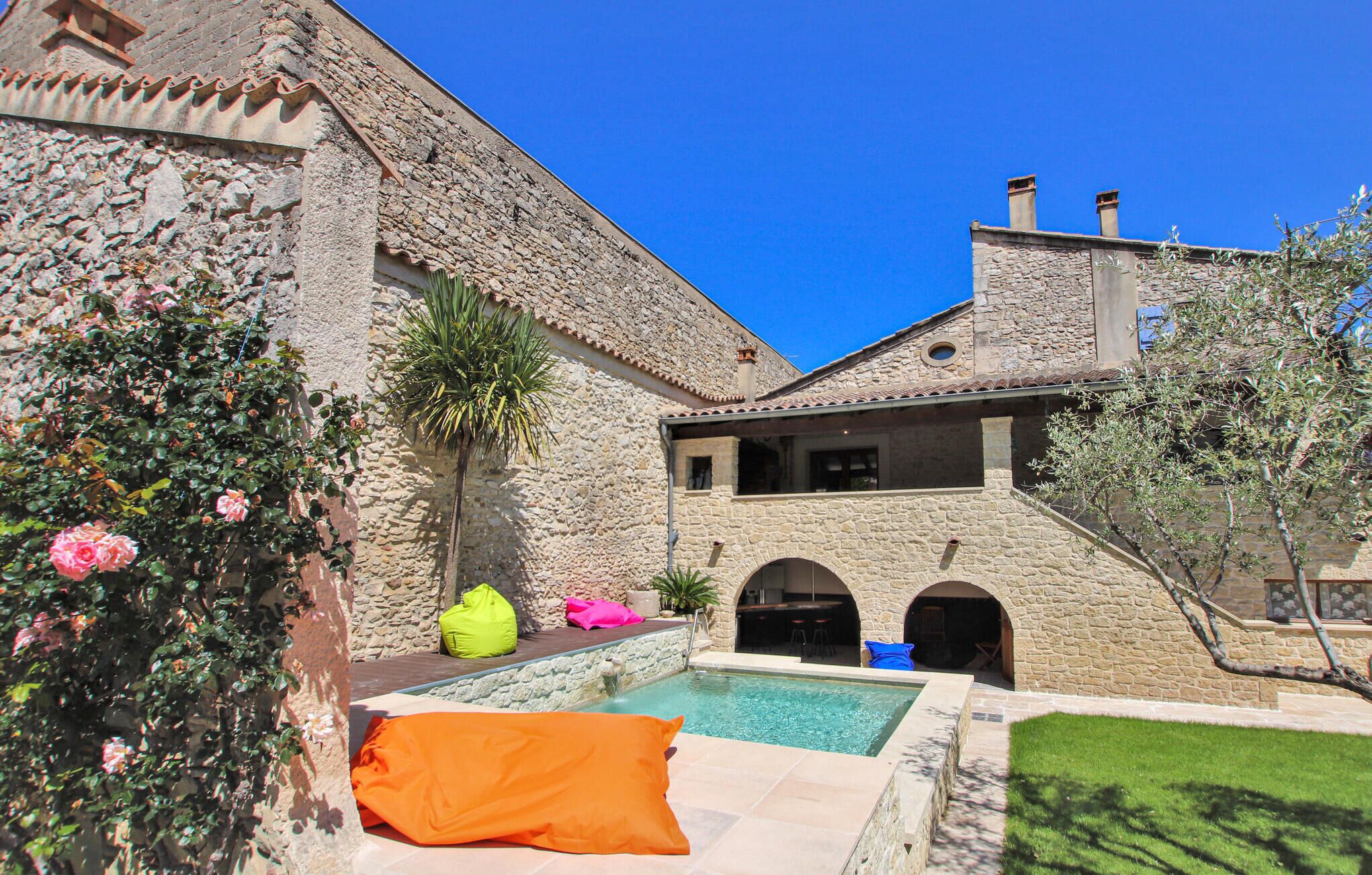 Ein Steinhaus mit Pool, Außenbereich und blauem Himmel.