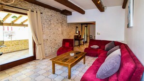 Una sala de estar con pared de piedra, techo de madera, un sofá rojo y una mesa de centro de madera.