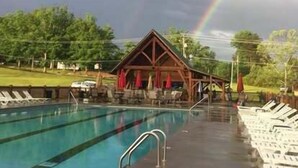 A swimming pool with lounge chairs and a covered seating area. - Breathtaking Views – No-Stair Entry, Hot Tub, Pool Table & Seasonal Pool Access (Sevierville)