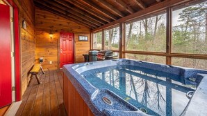 A wooden cabin with a hot tub, a red door, and a view of the forest. - Breathtaking Views – No-Stair Entry, Hot Tub, Pool Table & Seasonal Pool Access (Sevierville)
