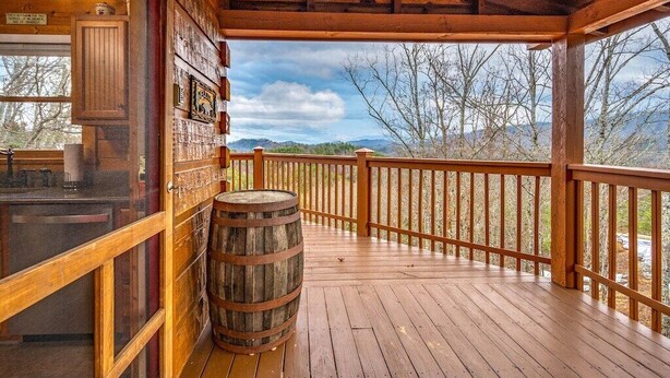 A wooden deck with a wooden barrel, a glass door, and a view of trees and mountains. - Breathtaking Views – No-Stair Entry, Hot Tub, Pool Table & Seasonal Pool Access (Sevierville)