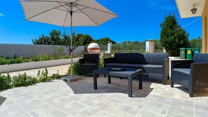 Une terrasse extérieure avec un canapé, une table et un parasol.