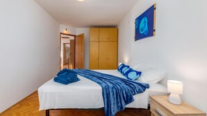 Une chambre à coucher comprenant un lit, une table de chevet, une armoire en bois et une œuvre d’art accrochée au mur.