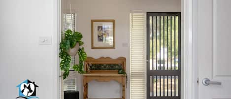 Een hal met een houten bankje, een potplant en een lijst aan de muur.