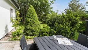 A patio with a table and chairs, a white building, and a large coniferous tree. - Amazing home in Nørre Nebel with WiFi (Nørre Nebel)