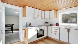 A modern kitchen with white cabinets, a built-in oven, a coffee maker, and a window with a view of trees. - Amazing home in Nørre Nebel with WiFi (Nørre Nebel)
