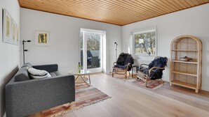 A modern living room with a grey sofa, two armchairs, a wicker side table, and a large window with a view of the outdoors. - Amazing home in Nørre Nebel with WiFi (Nørre Nebel)