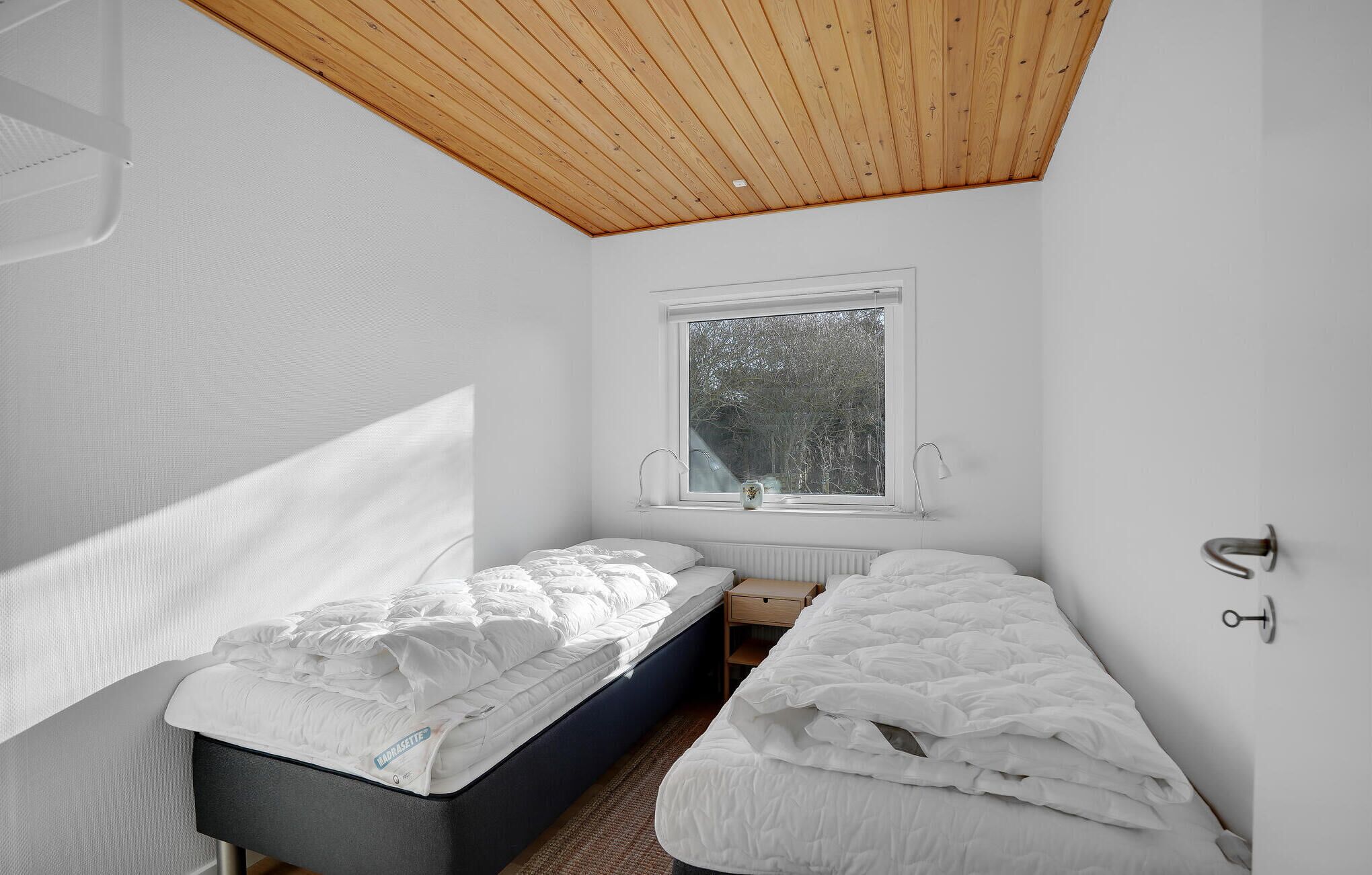 Ein Schlafzimmer mit zwei Betten, einem Fenster und einer Holzbalkendecke.