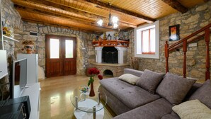 Ein gemütliches Wohnzimmer mit Kamin aus Stein, Holzbalken an der Decke und einer bequemen Couch.