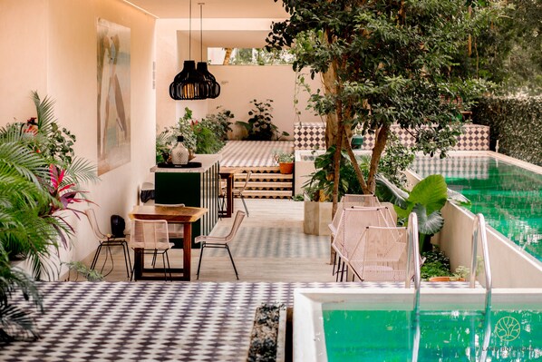 A poolside area with a checkered floor, lounge chairs, and a dining table.