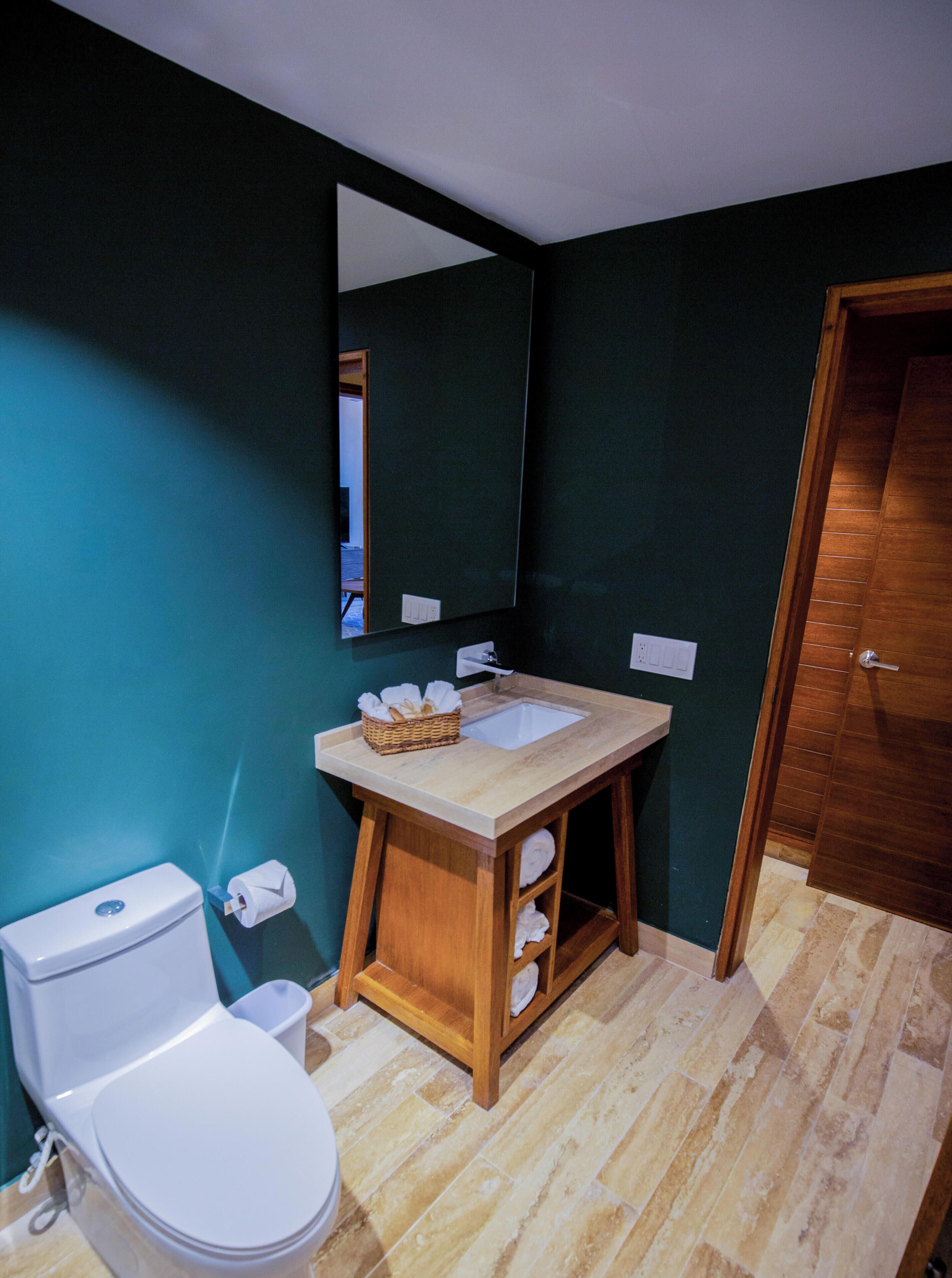 A bathroom with a white toilet, a wooden vanity with a sink, and a mirror above it.