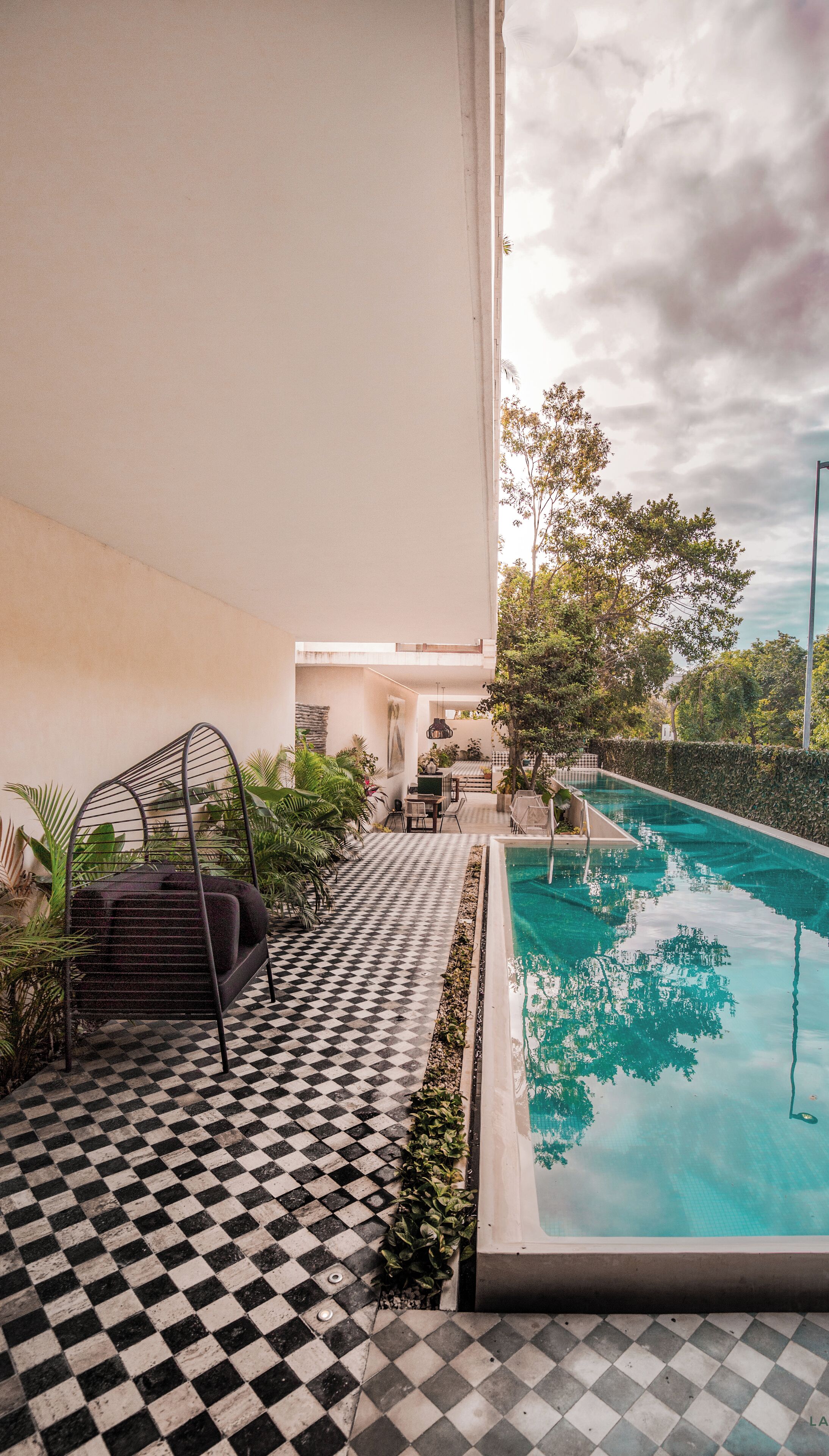 A pool area with a checkered floor, a lounge chair, and a view of the pool.