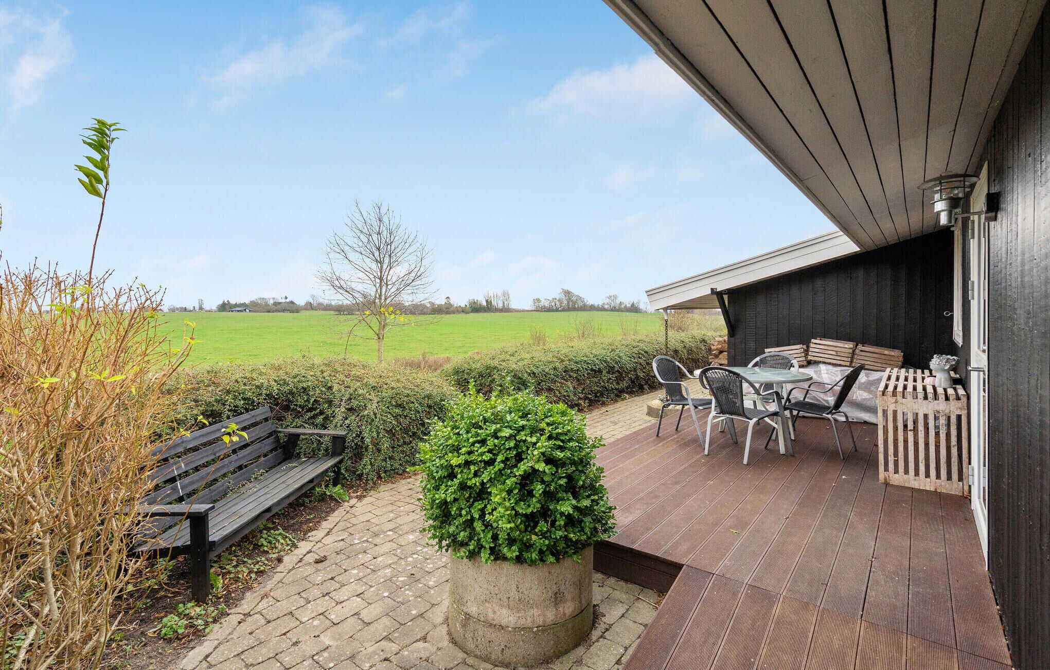 Eine Terrasse mit Tisch, Stühlen, einer Bank und einem Blumentopf.
