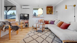 Ein modernes Wohnzimmer mit einer Couch, einem Fernseher und einem Holzstuhl.