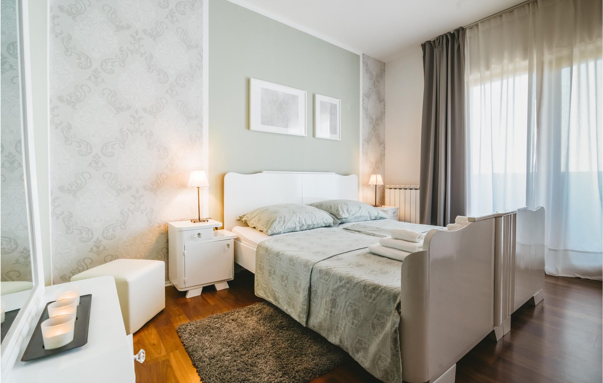 Une chambre à coucher avec un lit, des tables de chevet, un radiateur et une fenêtre avec des rideaux.