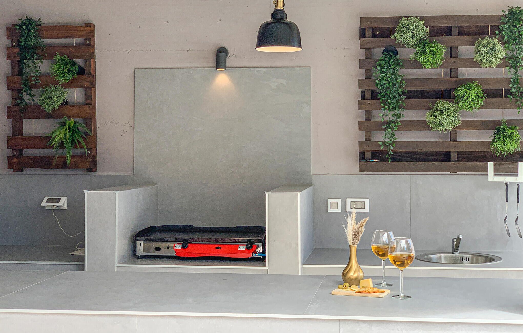 A modern kitchen with a built-in grill, wooden plant shelves, and a wine glass setup.