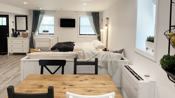 Un dormitorio moderno y funcional con cama, mesita de noche y pequeño escritorio.