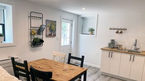 Una cocina moderna con armarios blancos, una mesa de comedor de madera y una silla negra.