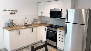Una cocina moderna con gabinetes blancos, un refrigerador de acero inoxidable, un microondas y una estufa.