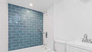 Un baño con una bañera blanca, un inodoro blanco y un lavabo con espejo.