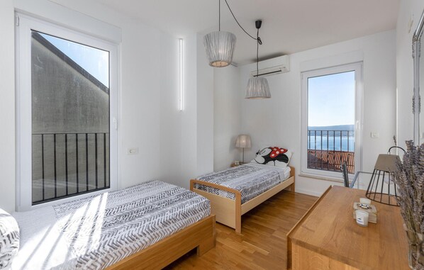 Un dormitorio con dos camas, un escritorio de madera, una lámpara y vistas al mar.