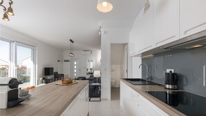 A modern kitchen with a central island, a built-in oven, and a large window overlooking a balcony. - 3 bedroom gorgeous home in Crikvenica (Crikvenica)