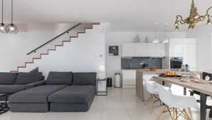 A modern apartment with a grey sectional sofa, a staircase, a kitchen with white cabinets, and a dining area with white chairs. - 3 bedroom gorgeous home in Crikvenica (Crikvenica)