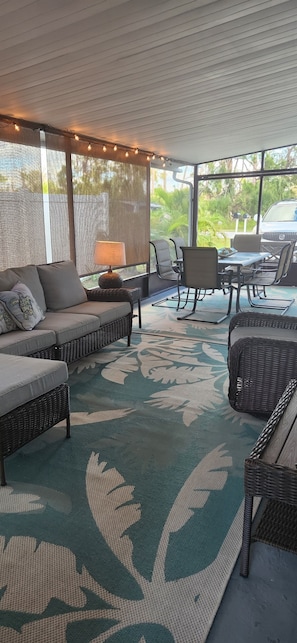 Relax in a comfortable outdoor seating area with a sofa, chairs, and table, surrounded by lush greenery.