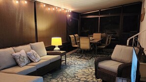 A cozy indoor seating area with a sofa, chairs, and a table, featuring a patterned rug and string lights. - AQUAHOLIC VISTA (Englewood)