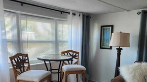 A room with a round table and four chairs, a sofa, a lamp, and a framed picture on the wall. - AQUAHOLIC VISTA (Englewood)